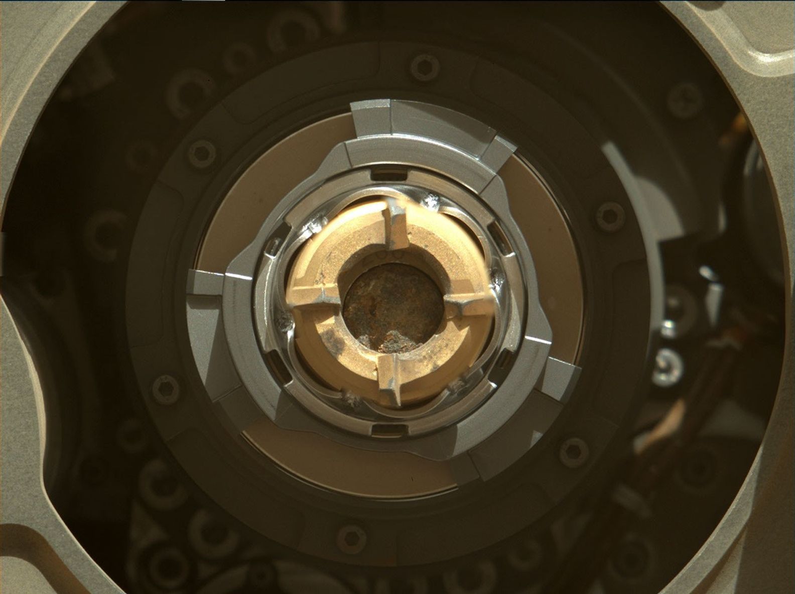 NASA's Perseverance rover shows a sample tube with its cored-rock contents inside. The bronze-colored outer-ring is the coring bit. The lighter-colored inner-ring is the open end of the tube, and inside is a rock core sample slightly thicker than a pencil. In a later image, the rock sample was not clearly evident inside the tube.