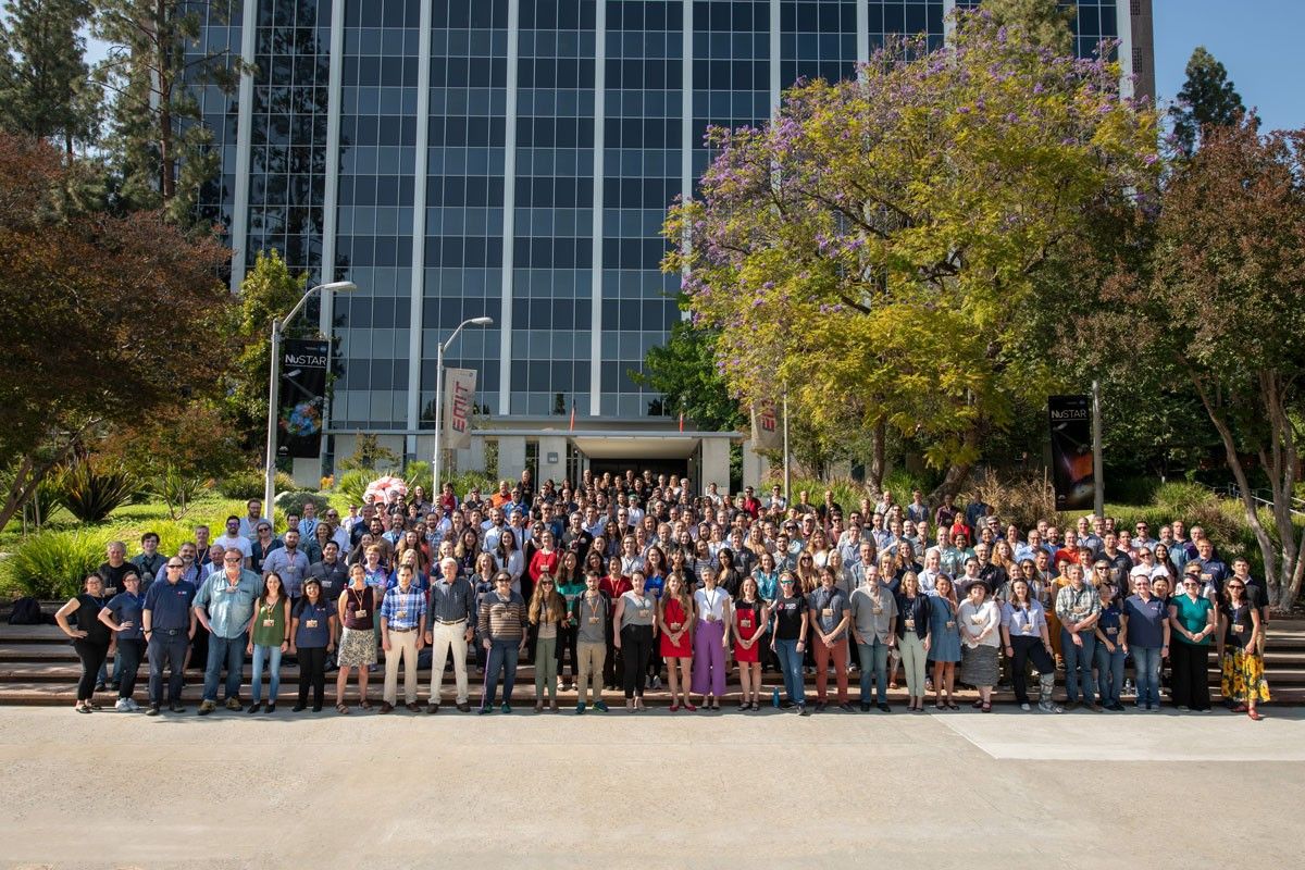 Members of the Perseverance rover Science Team pose in front of building at NASA's Jet Propulsion Laboratory.