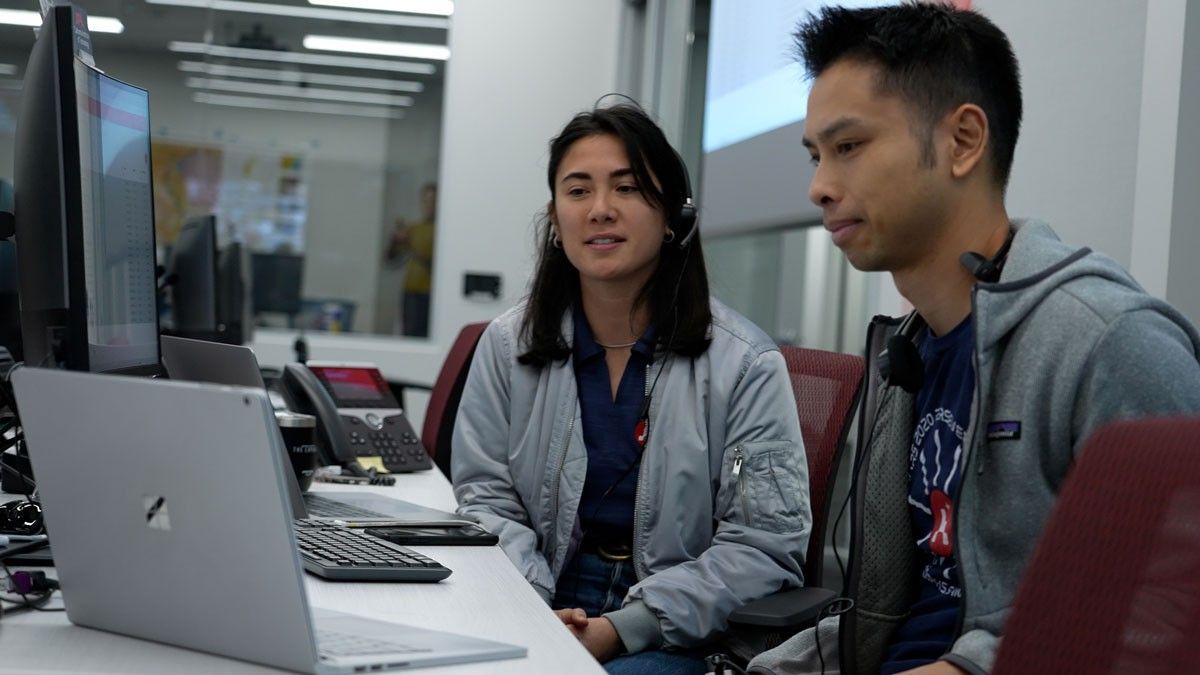 Image inside the control room with two Mars team members interacting virtually with student honorees.
