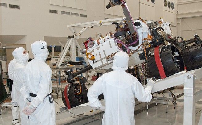 NASA's next Mars rover, Curiosity, stretches its robotic arm upward during Sept. 3, 2010, tests on a tilt table in a clean room at NASA's Jet Propulsion Labotatory, Pasadena, Calif. Test operators in clean room garb monitor the motions simulating maneuvers that the rover might make while on a sloped surface on Mars.