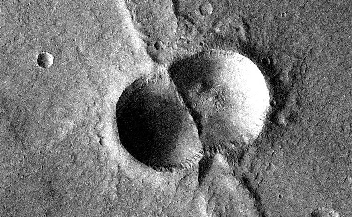 If a meteorite breaks in two shortly before hitting the ground, the typical bowl shape of a single impact crater becomes doubled.