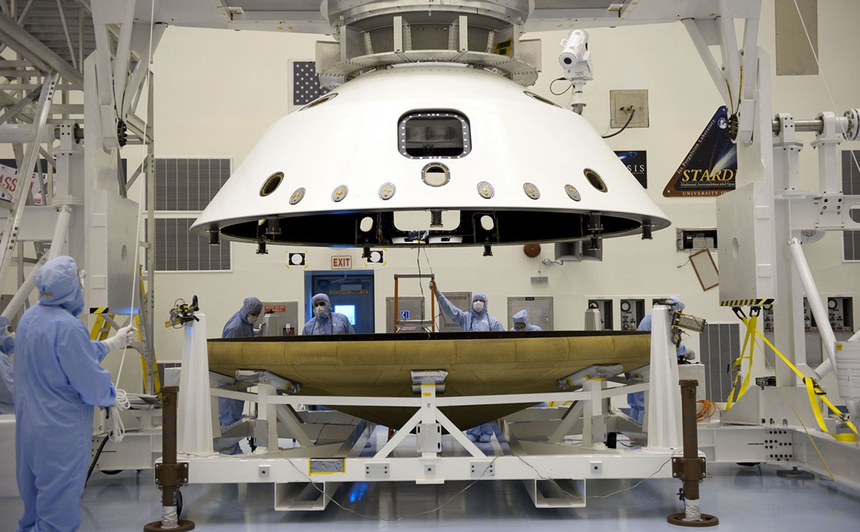 At the Payload Hazardous Servicing Facility at NASA's Kennedy Space Center in Florida, technicians, using an overhead crane, separate the two components of the aeroshell, an element of NASA's Mars Science Laboratory (MSL), after testing.