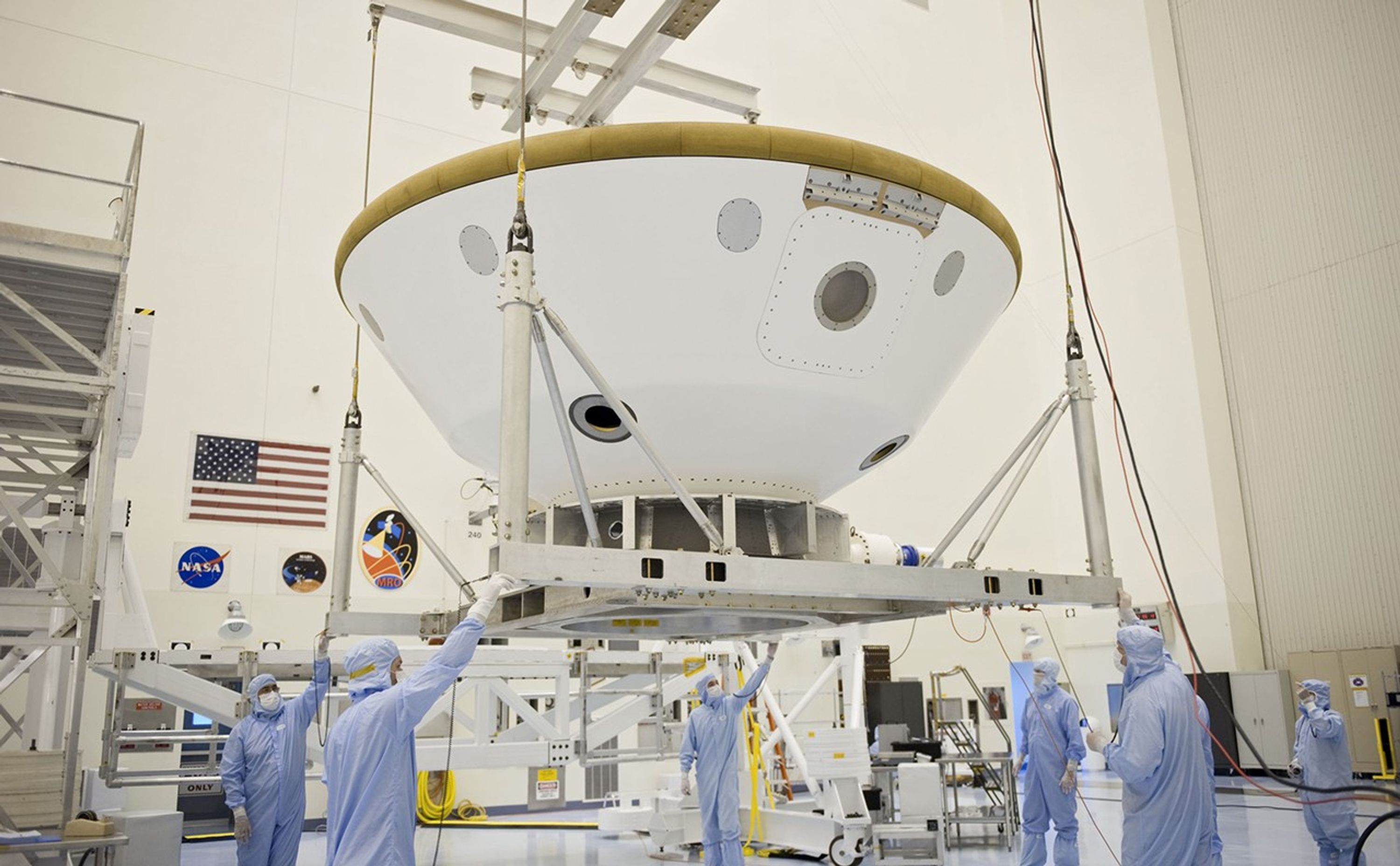 At the Payload Hazardous Servicing Facility at NASA's Kennedy Space Center in Florida, technicians using an overhead crane, move the aeroshell, a component of NASA's Mars Science Laboratory (MSL), back to a work stand after a spin and balance test.