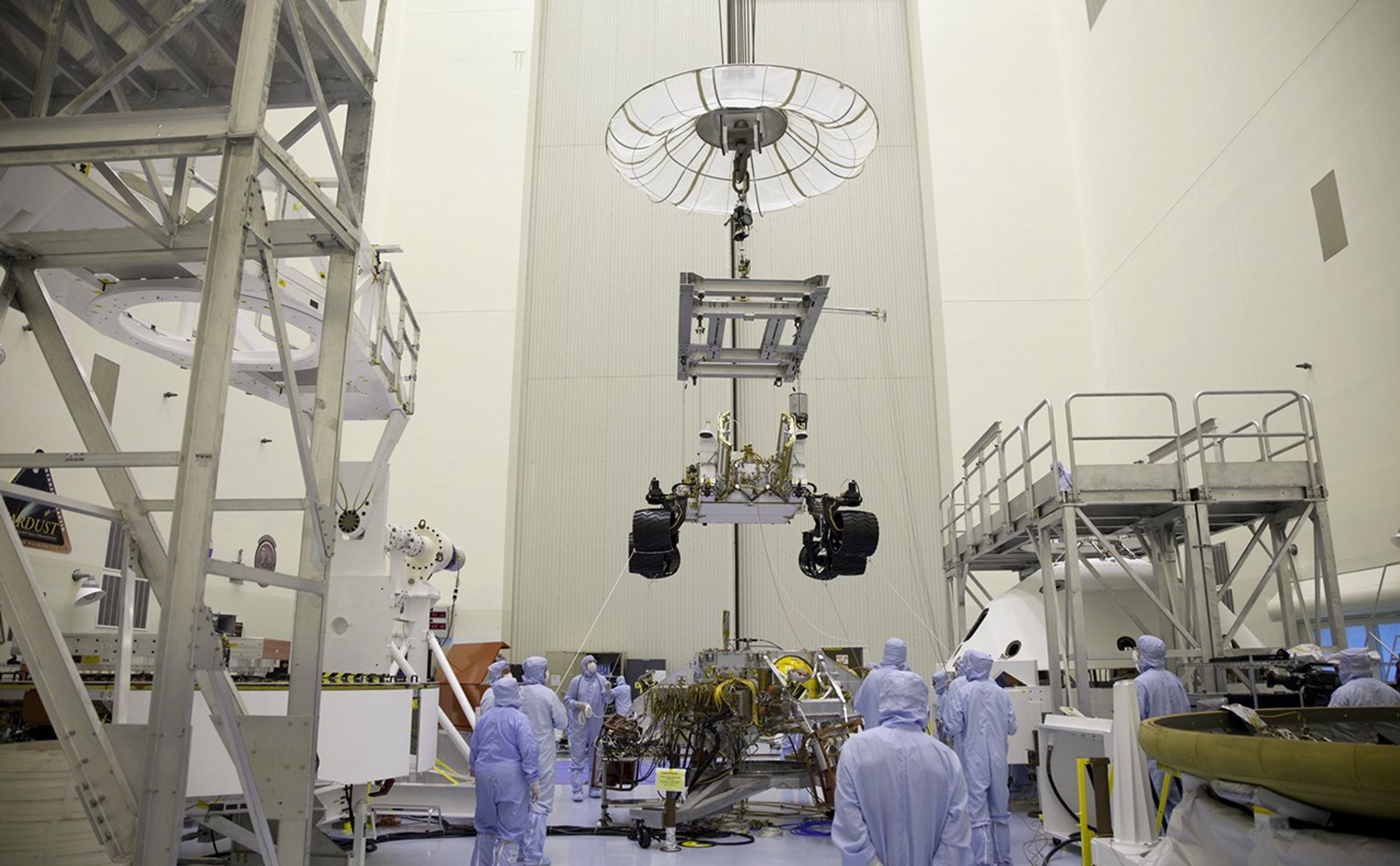 Technicians, at the Payload Hazardous Servicing Facility at NASA's Kennedy Space Center in Florida, use an overhead crane to move NASA's Mars Science Laboratory (MSL) rover, known as Curiosity, to the high bay floor where the instrument mast and science boom will undergo deployment testing.