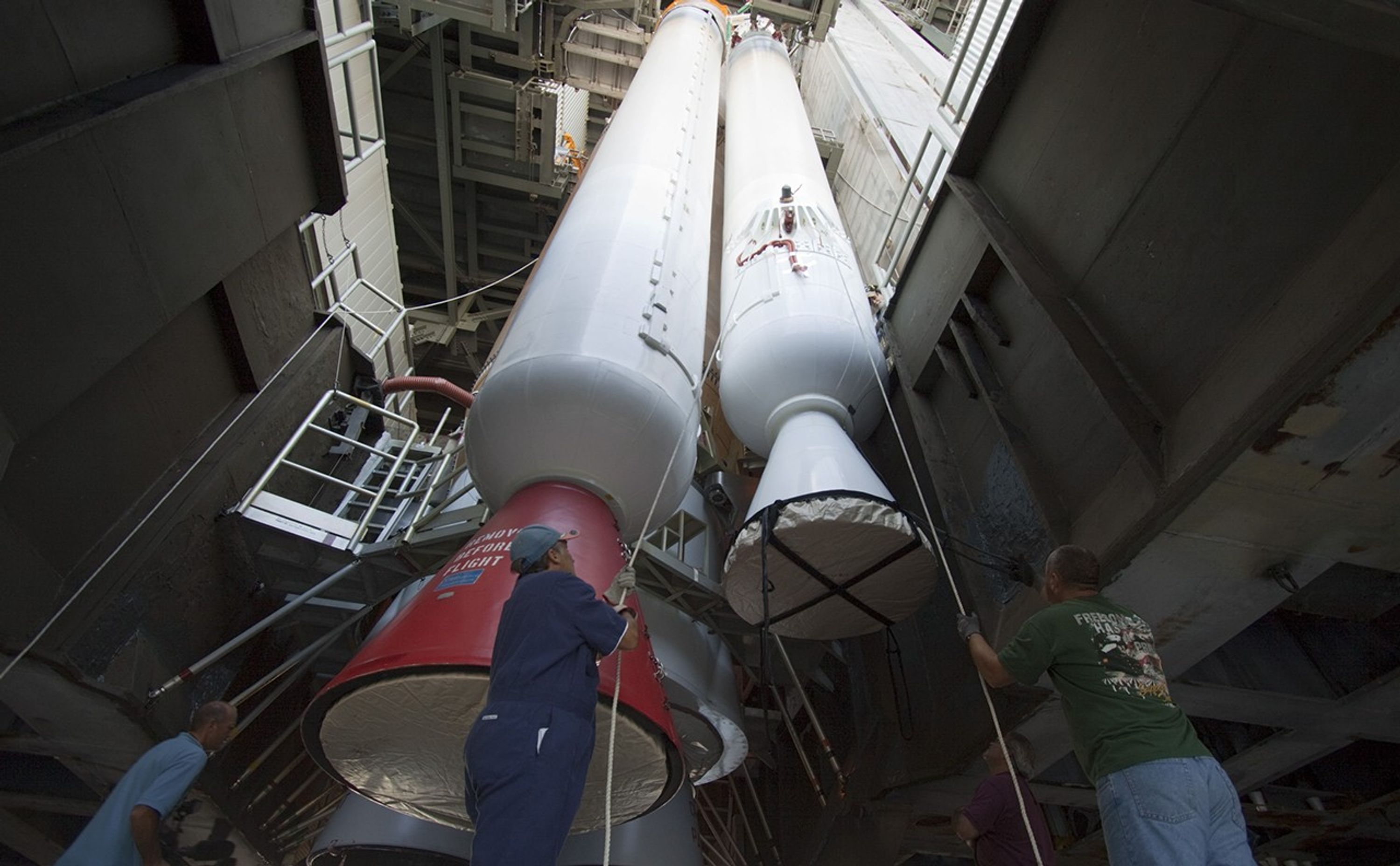 Inside the Vertical Integration Facility at Space Launch Complex 41 on Cape Canaveral Air Force Station in Florida, technicians using an overhead crane guide the final solid rocket motor into position for mating to the first stage of a United Launch Alliance Atlas V rocket.
