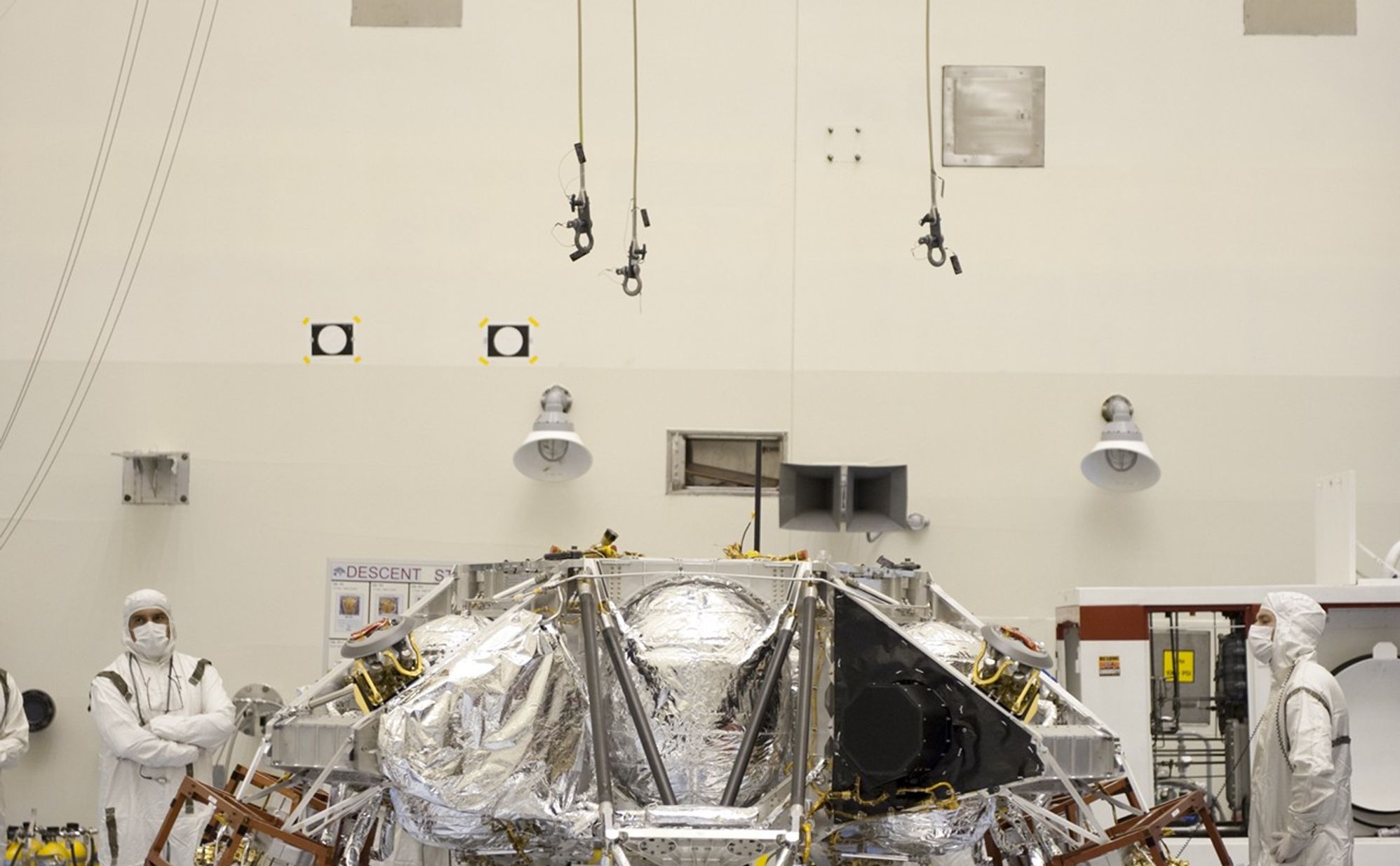 At the Payload Hazardous Servicing Facility at NASA's Kennedy Space Center in Florida, an overhead crane is being lowered over a rocket-powered descent stage for integration with NASA's Mars Science Laboratory (MSL) rover, known as Curiosity.