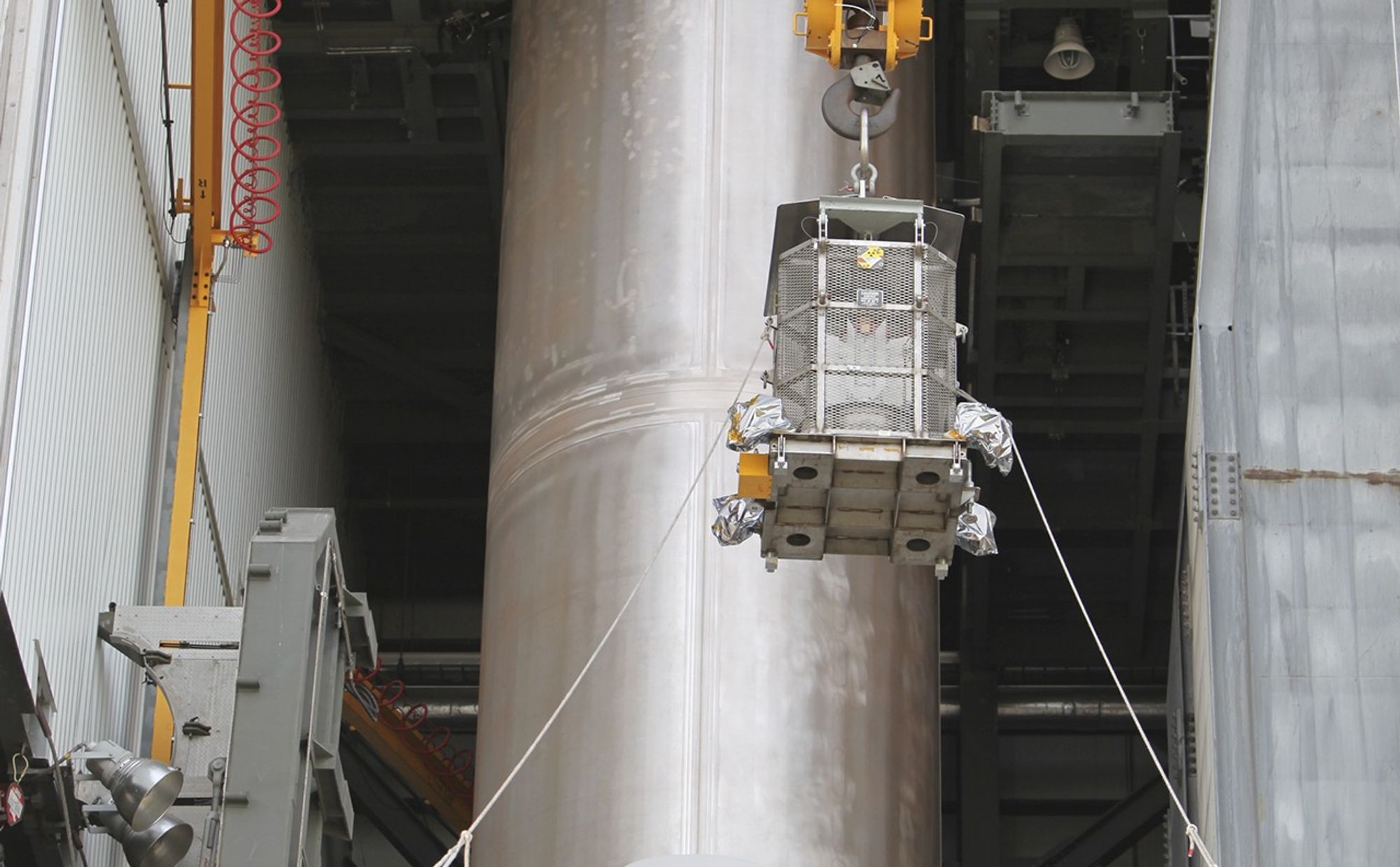 Enclosed in the protective mesh container known as the "gorilla cage," the multi-mission radioisotope thermoelectric generator (MMRTG) for NASA's Mars Science Laboratory (MSL) mission is lifted up the side of the Vertical Integration Facility at Space Launch Complex 41.