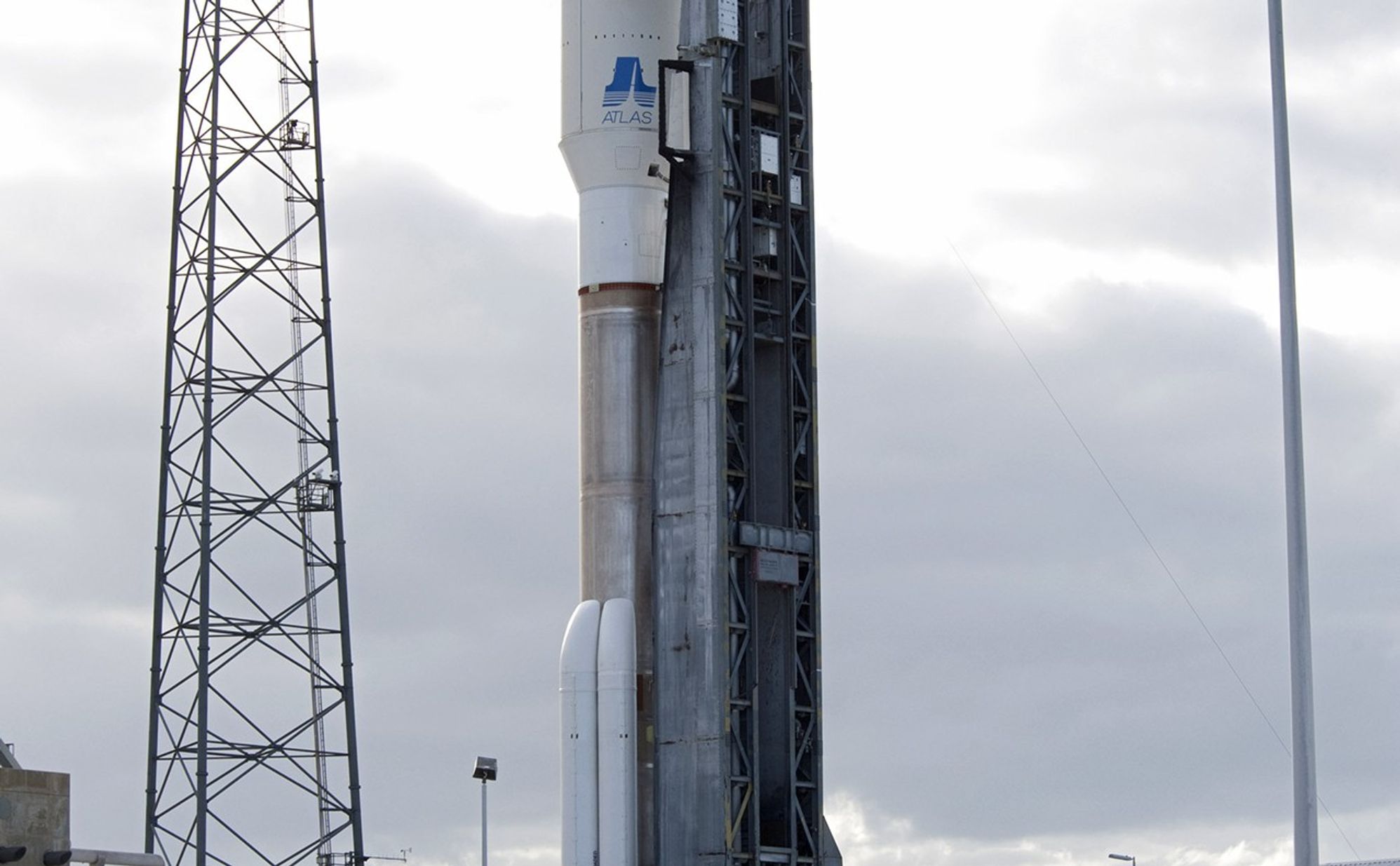 On Cape Canaveral Air Force Station in Florida, one of three lightning masts, at left, protects the 197-foot-tall United Launch Alliance Atlas V rocket as it rolls from the safety of the Vertical Integration Facility (VIF) at Space Launch Complex-41 to the pad's surface.