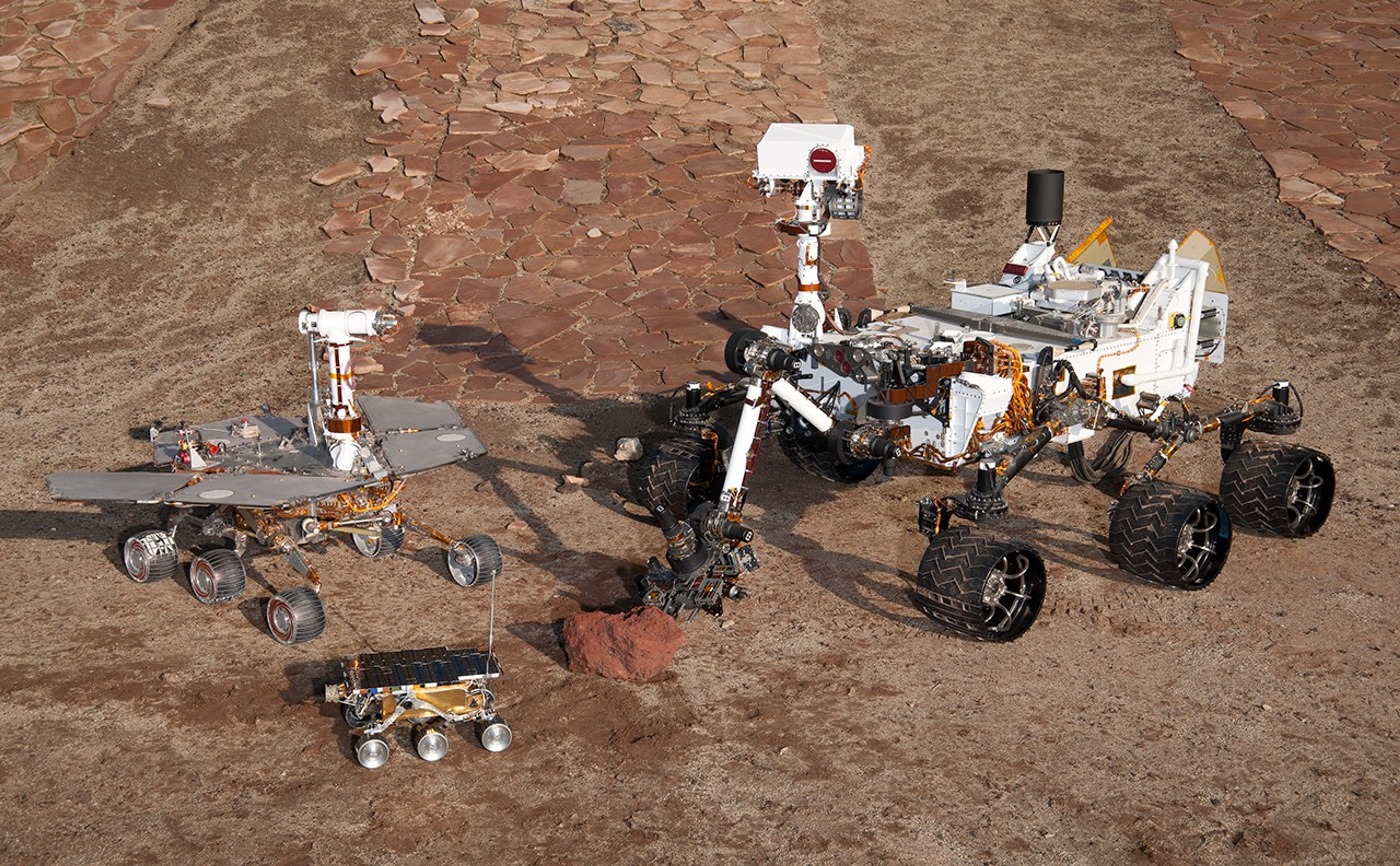This grouping of two test rovers and a flight spare provides a graphic comparison of three generations of Mars rovers developed at NASA's Jet Propulsion Laboratory, Pasadena, Calif. The setting is JPL's Mars Yard testing area.