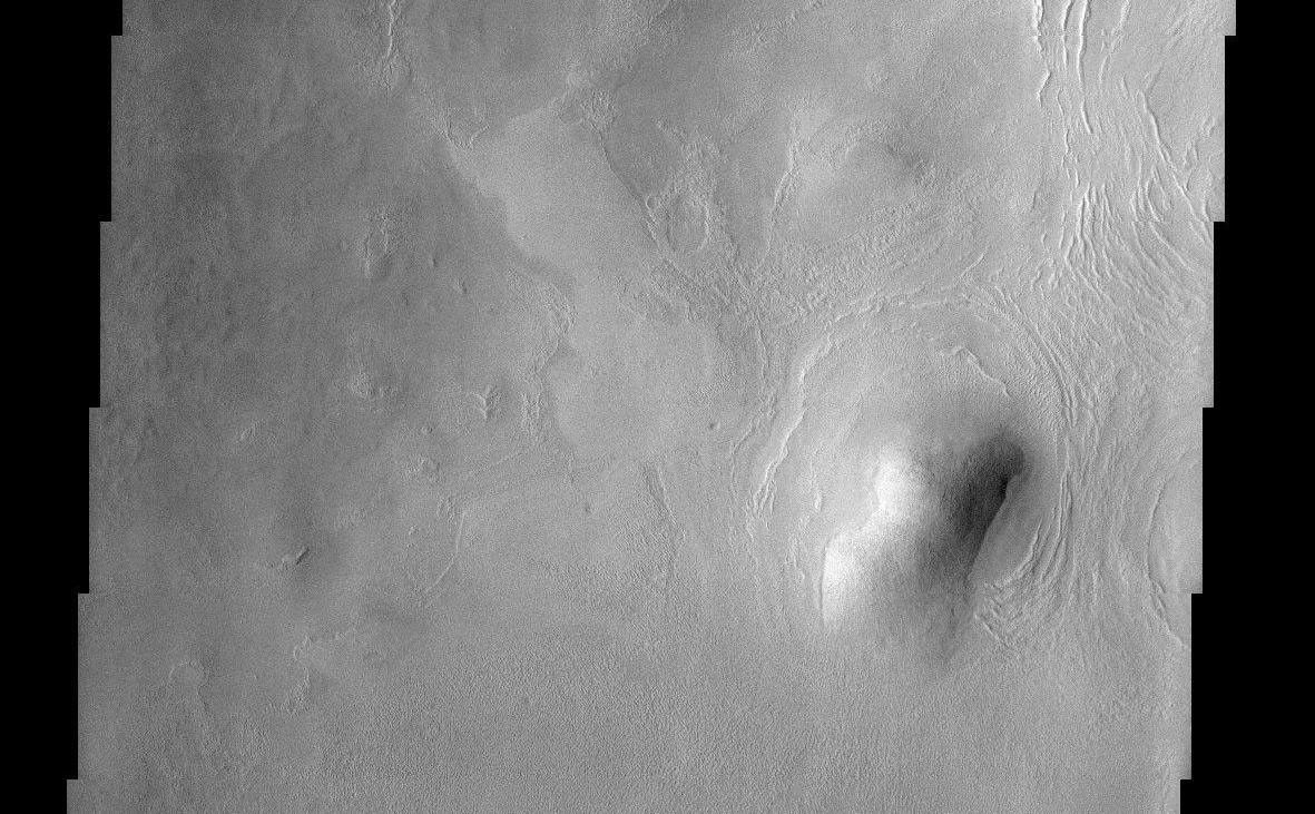 This THEMIS image of rounded hills and ridges in Arcadia Planitia shows a very intriguing geomorphic feature that may be attributed to the presence of an icy-rock mixture of material. Smooth aprons of material are observed to be preferentially located on the cold, north facing slopes of hills and extend further and beyond the deposits located on other sides. These smooth deposits are in stark contrast to the more rough surfaces that dominate the scene and it has been suggested that they represent a preserved mixture of ice and rock. How exactly this deposit forms still remains a mystery. They may have been "pasted" onto the slopes and preserved on the cold facing sides or they may represent the result of downslope motion of material that is enhanced by the presence of ground ice. In either case, this interesting observation suggests that ground ice may still play an important role in the formation and preservation of martian surface features.