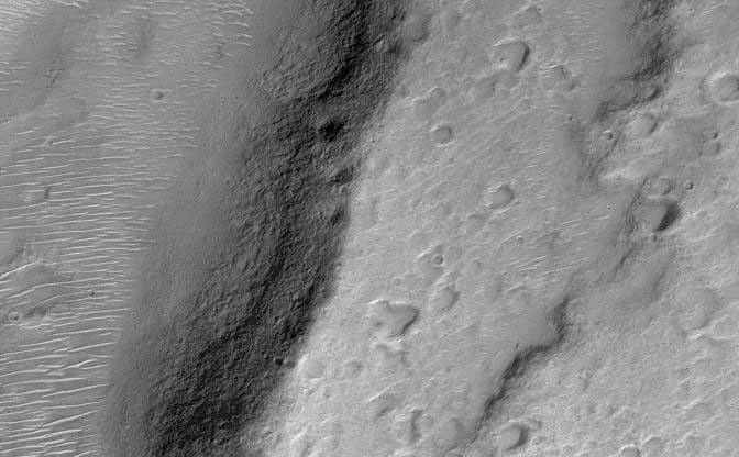 Tyrrhenna Patera is thought to be an ancient volcano. It is located in Hesperia Planum in the martian southern hemisphere. The Mars Orbiter Camera recently acquired this view of escarpments and valleys on the lower northeast flank of the volcano. Small, bright dunes cover low areas such as valley and crater floors. The picture is illuminated from the lower right and covers an area 3 kilometers (1.9 miles) across.