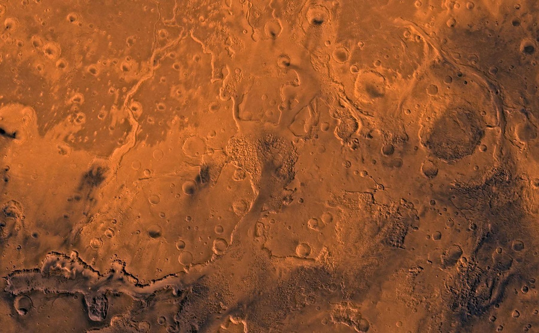 A color image of the south Chryse basin Valles Marineris outflow channels on Mars; north toward top. The scene shows on the southwest corner the chaotic terrain of the east part of Valles Marineris and two of its related canyons: Eos and Capri Chasmata (south to north). Ganges Chasma lies directly north. The chaos in the southern part of the image gives rise to several outflow channels, Shalbatana, Simud, Tiu, and Ares Valles (left to right), that drained north into the Chryse basin. The mouth of Ares Valles is the site of the Mars Pathfinder lander.This image is a composite of Viking medium-resolution images in black and white and low-resolution images in color. The image extends from latitude 20 degrees S. to 20 degrees N. and from longitude 15 degrees to 53 degrees; Mercator projection.The south Chryse outflow channels are cut an average of 1 km into the cratered highland terrain. This terrain is about 9 km above datum near Valles Marineris and steadily decreases in elevation to 1 km below datum in the Chryse basin. Shalbatana is relatively narrow (10 km wide) but can reach 3 km in depth. The channel begins at a 2- to 3-km-deep circular depression within a large impact crater, whose floor is partly covered by a chaotic material, and ends in Simud Valles. Tiu and Simud Valles consist of a complex of connected channel floors and chaotic terrain and extend as far south as and connect to eastern Valles Marineris. Ares Vallis originates from discontinuous patches of chaotic terrain within large craters. In the Chryse basin the Ares channel forks; one branch continues northwest into central Chryse Planitia (Latin for plain) and the other extends north into eastern Chryse Planitia.