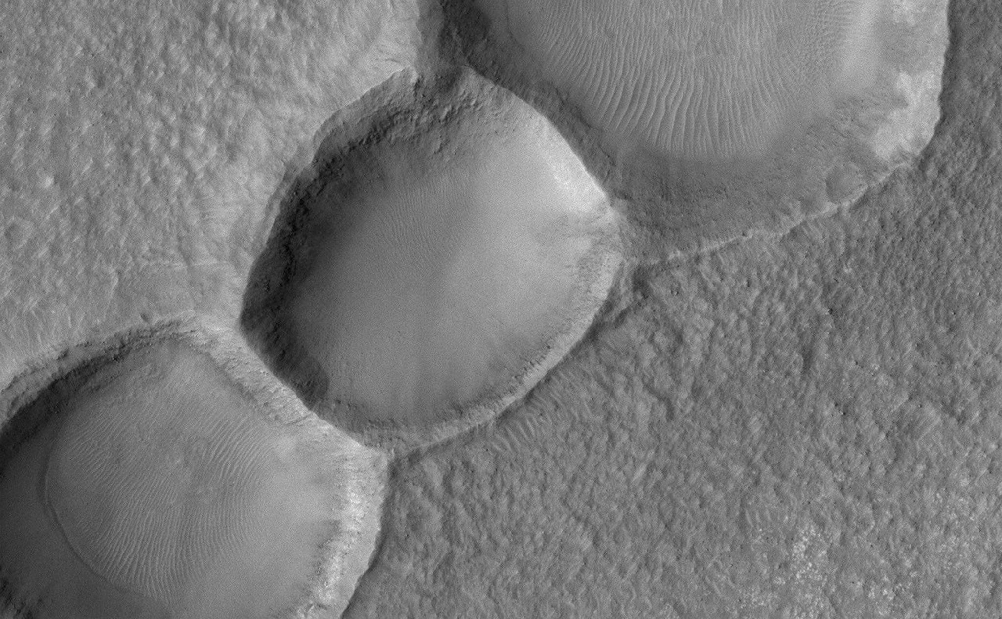 This Mars Global Surveyor (MGS) Mars Orbiter Camera (MOC) image shows a 1.5 meters per pixel (~5 ft/pixel) view of three aligned meteor impact craters on the floor of a much larger crater in the Noachis Terra region. The craters may have formed together from a single event in which the impactor (the meteor) was broken into three pieces.