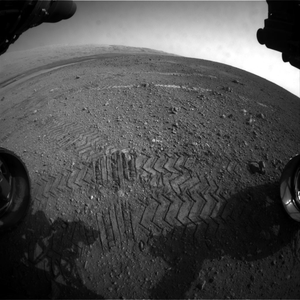 This image taken by a front Hazard-Avoidance camera on NASA's Curiosity shows track marks from the rover's first Martian drives. The rover's Bradbury Landing site and its first tire marks are seen at center, in the distance, while tracks from the second drive are in the foreground. Mount Sharp is on the horizon, which is curved to due to the camera's fisheye lens.