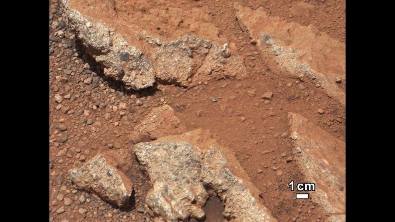 In this image from NASA's Curiosity rover, a rock outcrop called Link pops out from a Martian surface that is elsewhere blanketed by reddish-brown dust. The fractured Link outcrop has blocks of exposed, clean surfaces.