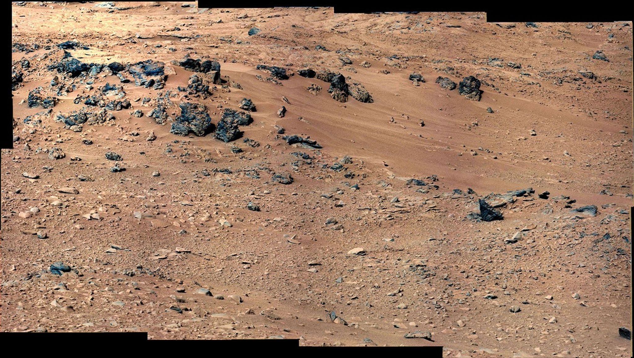 This patch of windblown sand and dust downhill from a cluster of dark rocks is the "Rocknest" site, which has been selected as the likely location for first use of the scoop on the arm of NASA's Mars rover Curiosity.