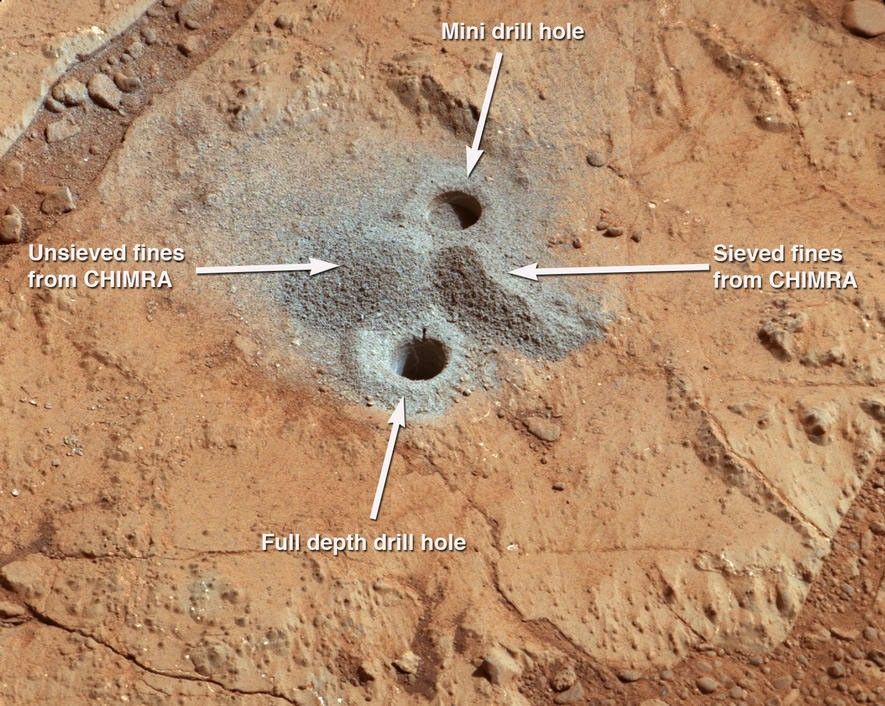 This image shows the first holes into rock drilled by NASA's Mars rover Curiosity, with drill tailings around the holes plus piles of powdered rock collected from the deeper hole and later discarded after other portions of the sample had been delivered to analytical instruments inside the rover.