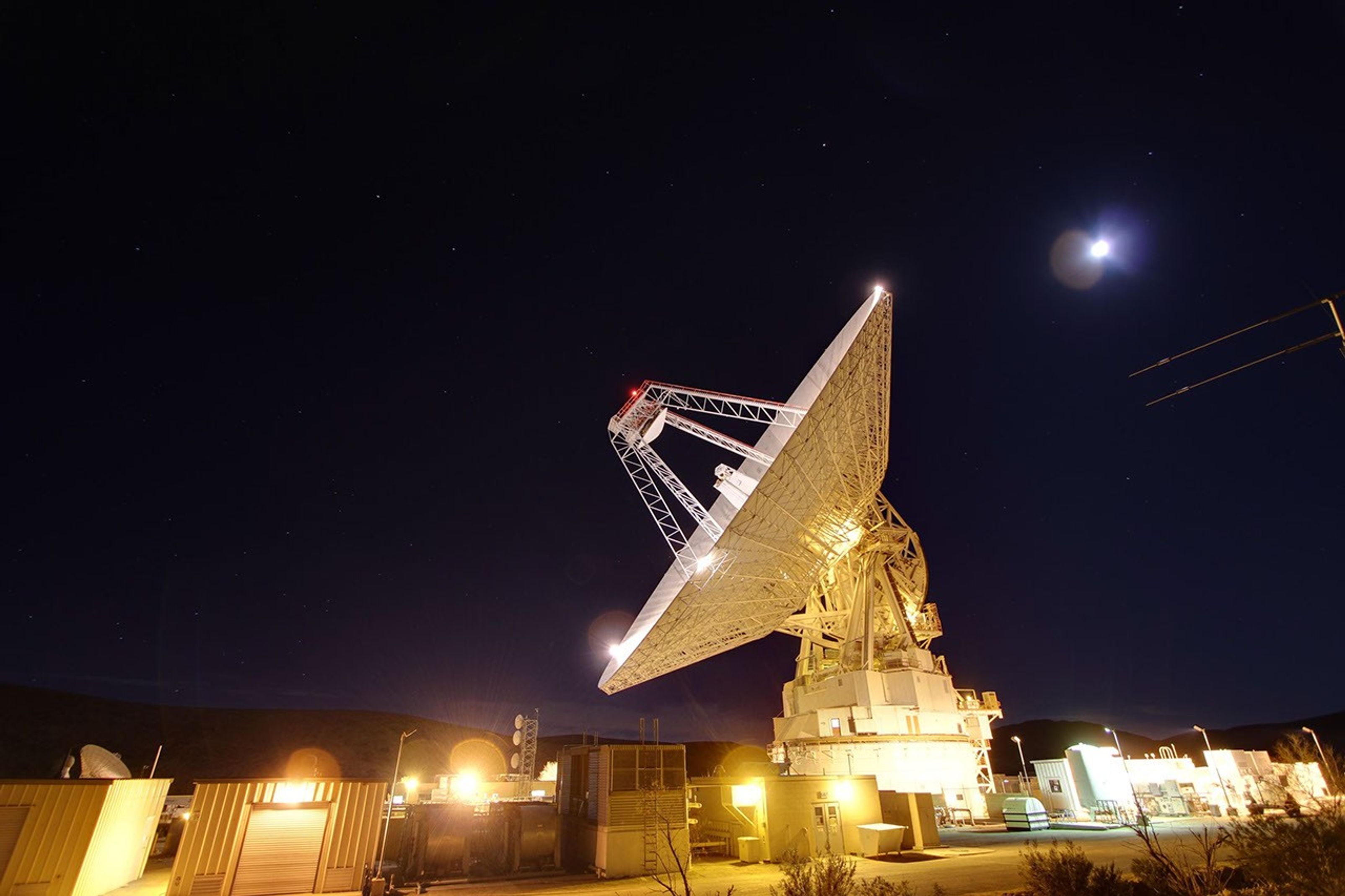 A radio antenna as big as a football field points to the night sky.