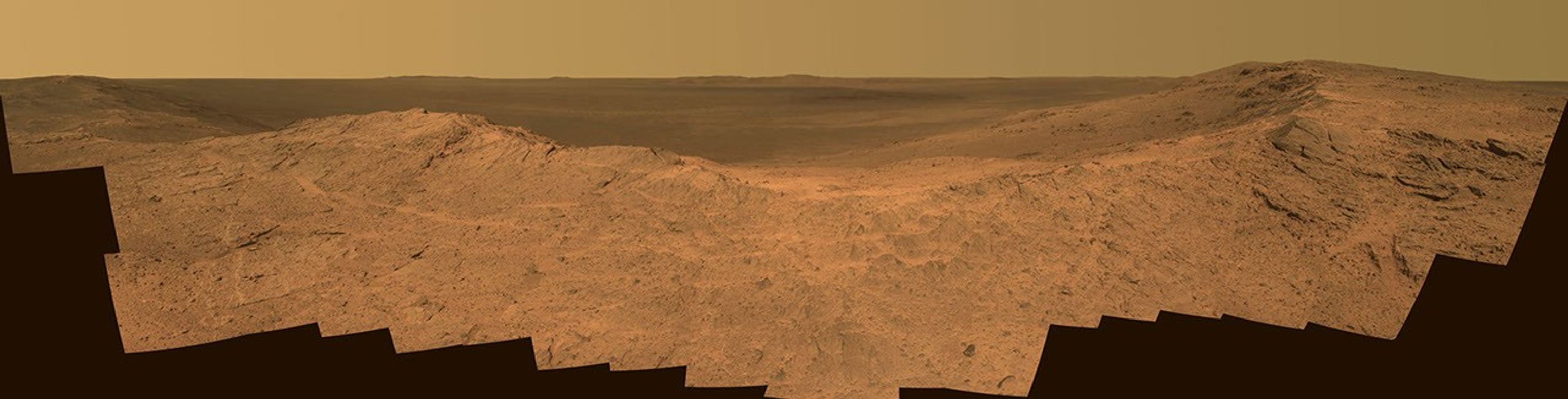 This scene from the panoramic camera (Pancam) on NASA's Mars Exploration Rover Opportunity catches "Pillinger Point," on the western rim of Endeavour Crater, in the foreground. The eastern rim of the crater is on the distant horizon. The scene merges many Pancam exposures taken on May 14, 2014.