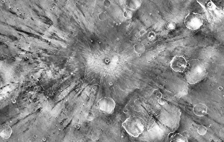 A small impact crater on Mars named Gratteri, 4.3 miles (6.9 km) wide, lies at the center of large dark streaks.