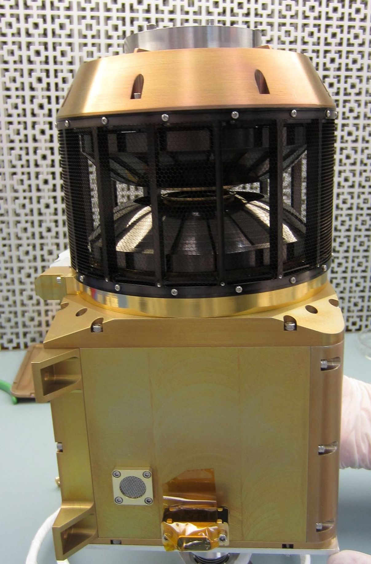 This image shows the wind analyzer instrument box that is yellow metal at the bottom, the top is a circular black cylinder.  The whole instrument is the size of a shoebox.