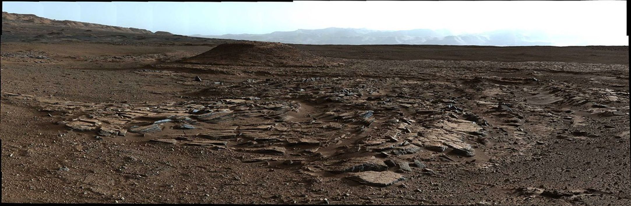 This April 4, 2014, image from Curiosity's Mastcam looks to the west of a waypoint on the rover's route to Mount Sharp. The mountain lies to the left of the scene. The image shows sets of sandstone beds inclined to the south (left), indicating progressive build-out of sediment toward Mount Sharp.