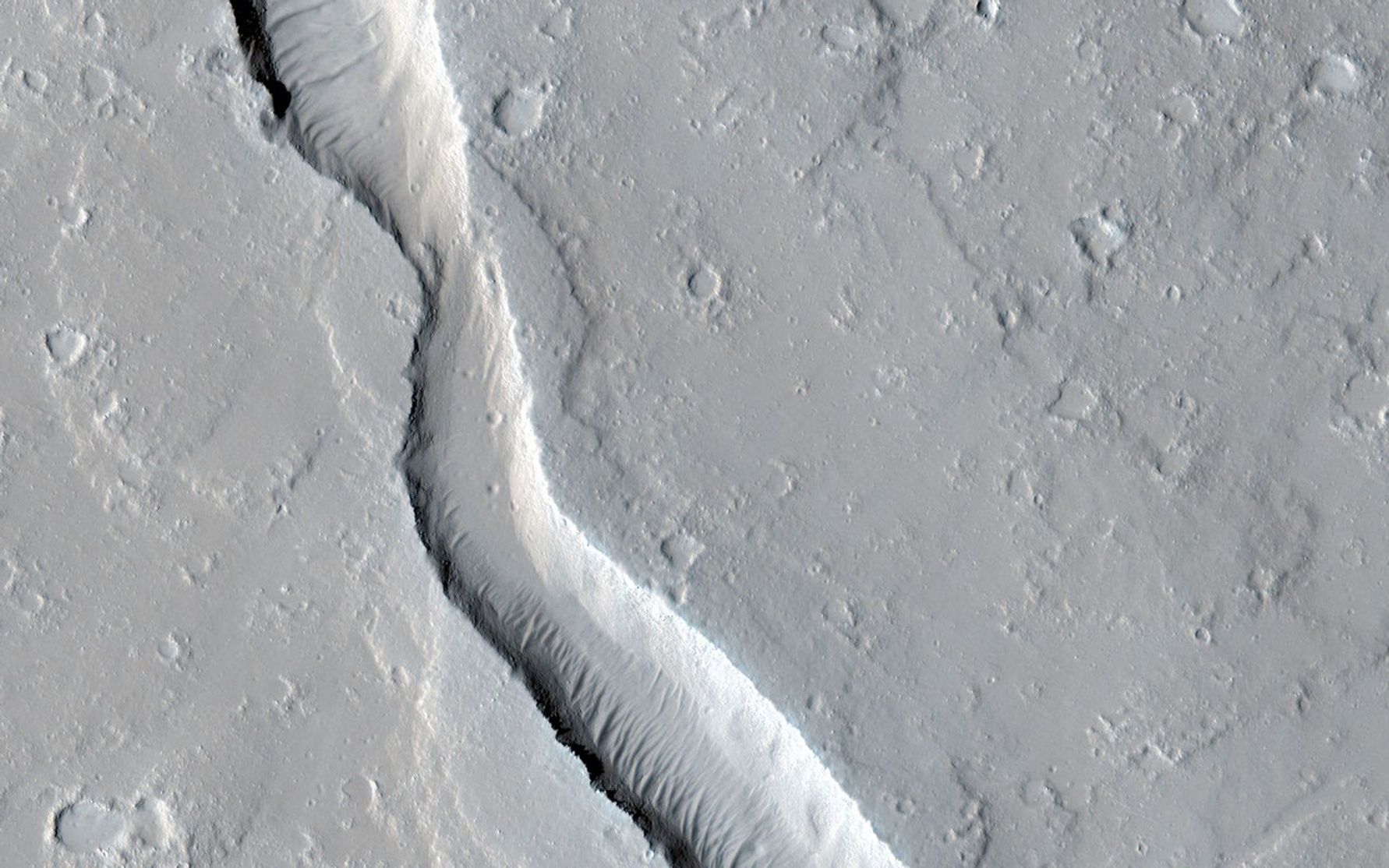 This image shows a lava channel, which lies just to the east of the largest volcano in the solar system: Olympus Mons.