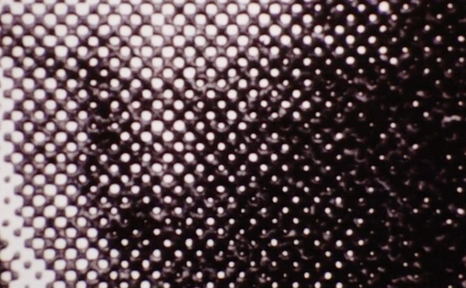 This image seems like a random series of light and dark grey dots when viewed up close. When seen from farther away the dots blend together to make an image of a tennis ball.