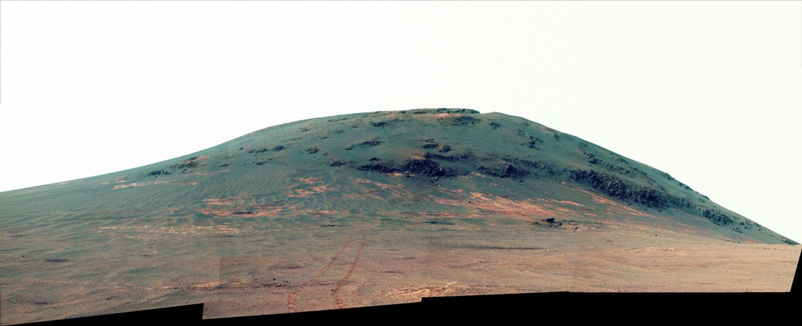 Wheel tracks from NASA's Mars rover Opportunity descending and departing the "Cape Tribulation" segment of Endeavour Crater's rim are visible in this April 21, 2017, view from the rover's Pancam. This version is presented in enhanced color to make differences in surface materials more visible.
