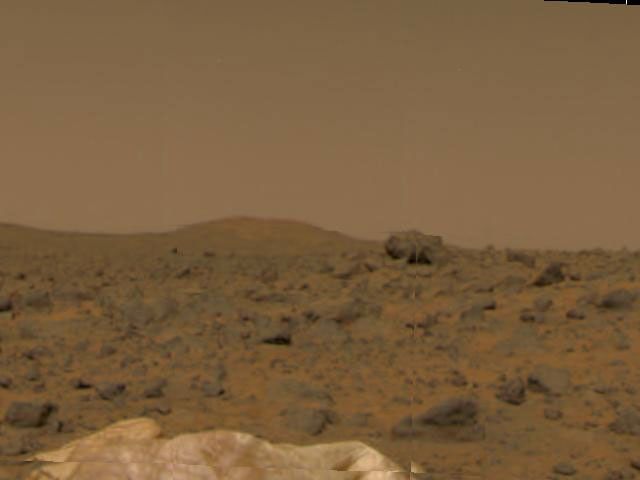 Portions of NASA's Mars Pathfinder's deflated airbags, a large rock in mid-field, and a hill in the background are seen during the spacecraft's first day on the Red Planet. Pathfinder successfully landed on Mars at 10:07 a.m. PDT on July 4, 1997.