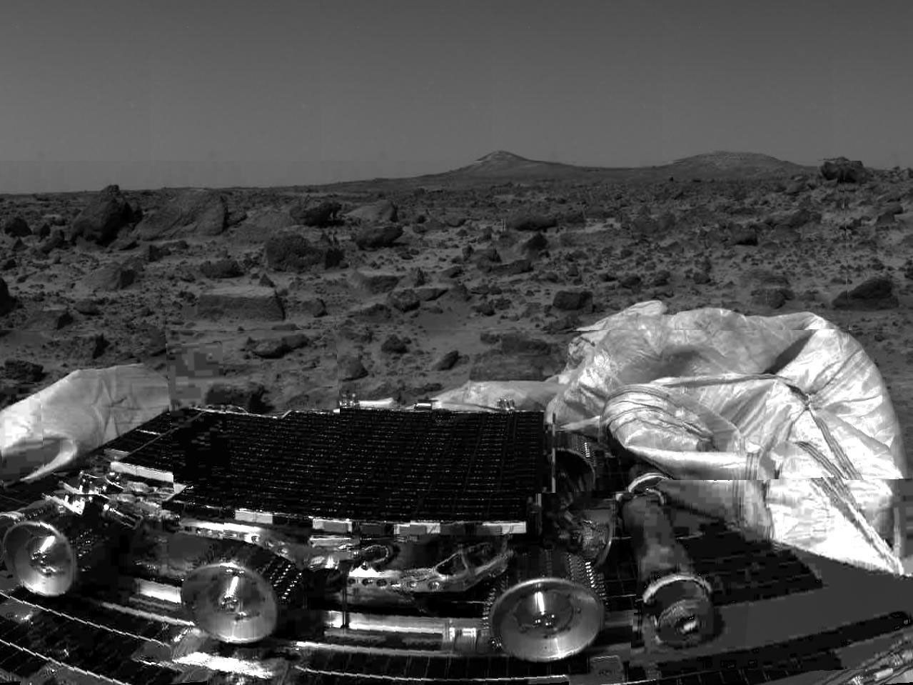 NASA's undeployed Sojourner rover is seen still latched to a lander petal in this image, taken on July 4, 1997, the lander's first day on Mars. Portions of a petal and deflated airbag are in the foreground.
