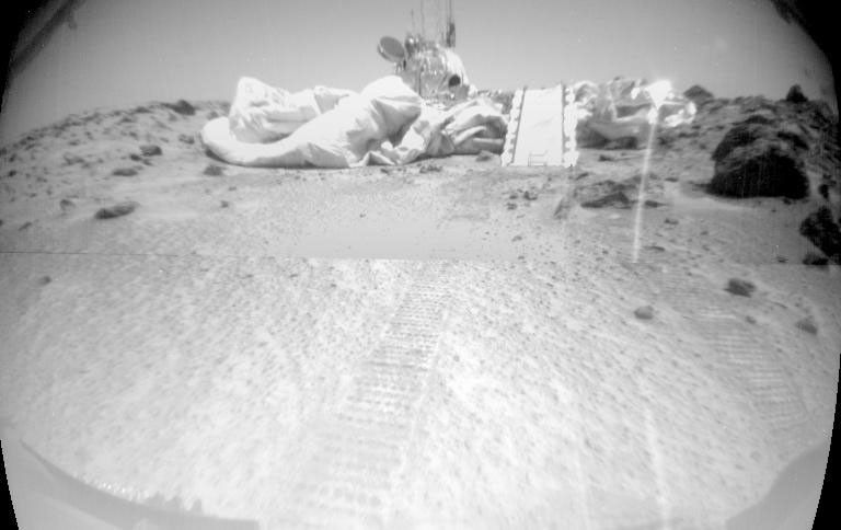 Taken from NASA's Mars rover Sojourner's forward camera, this image features a rover's-eye view of the Sagan Memorial Station; Sojourner's tracks are shown leading away from the spacecraft.