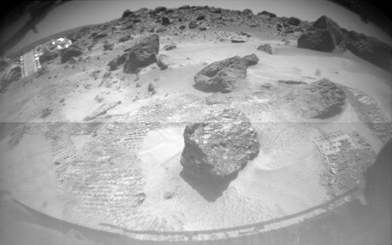 One of NASA's Sojourner's two front cameras took this image of the Sagan Memorial Station on Sol 6. The lander and its deployed rear ramp are at upper left, while several large rocks appear at center.