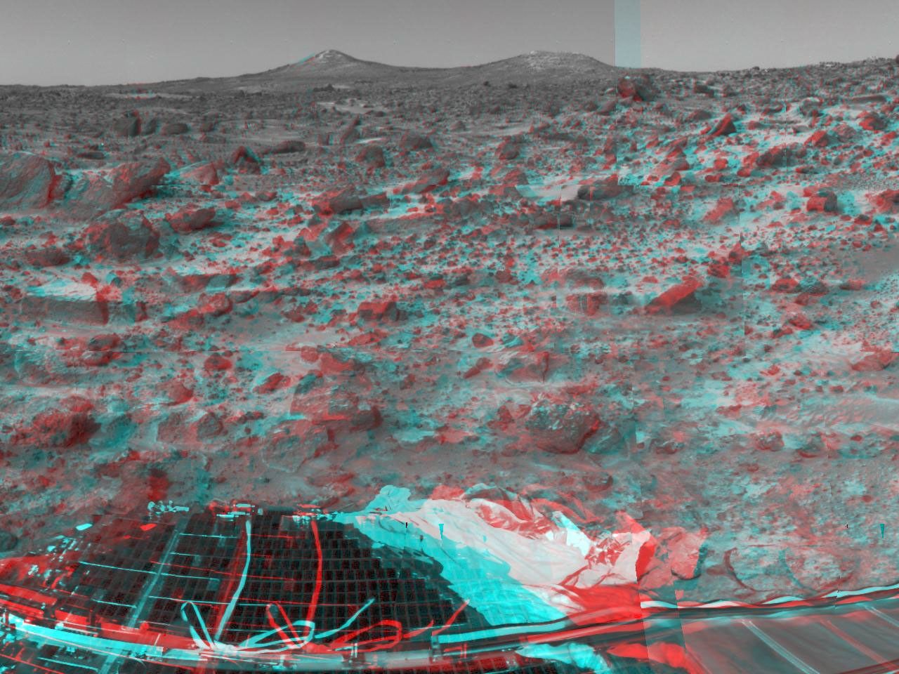 The two hills in the distance in this stereo image from NASA's Mars Pathfinder have been dubbed the 'Twin Peaks.' 3D glasses are necessary to identify surface detail.
