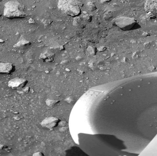 The patch of dark material toward the top of this picture taken by NASA's Viking 1 Lander is the debris kicked up by the impact of a protective cover ejected from the spacecraft.