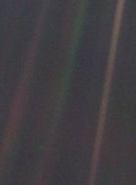 A dark, nearly black background with faint streaks of sunlight forming diagonal beams. In one of these beams, near the right side of the image, a minuscule, barely visible pale blue dot — Earth — stands out, appearing fragile and isolated against the vast emptiness of space. Taken on Feb. 14, 1990, by NASA's Voyager 1 spacecraft from 3.7 billion miles (6 billion kilometers) away, this iconic photograph underscores the profound vastness of the cosmos and Earth's tiny presence within it.