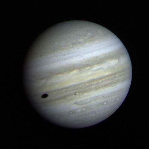 Jupiter's satellite Io poses before the giant planet in this photo returned January 17, 1979. The satellite's shadow can be seen falling on the face of Jupiter at left. Io is traveling from left to right in its orbit around Jupiter.