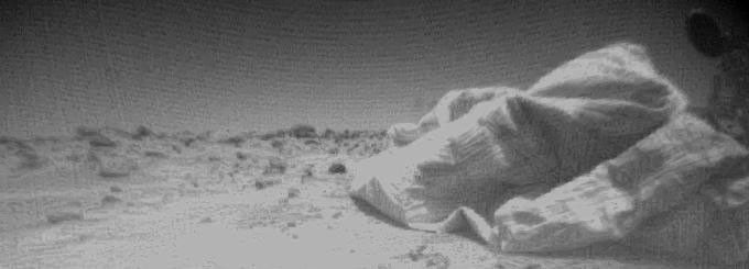 This is one of the first images taken by one of NASA's three Sojourner rover cameras on July 7, 1997. At right, portions of the lander's deflated airbags and circular high-gain antenna are visible.