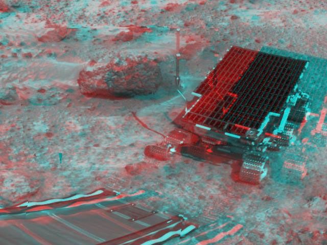 At right, NASA's Sojourner has traveled off the lander's rear ramp and onto the surface of Mars. The rock 'Barnacle Bill' and the rear ramp is to the left of Sojourner. 3D glasses are necessary to identify surface detail.