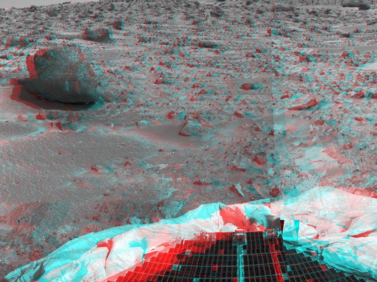 This image from NASA's Mars Pathfinder shows the large rock nicknamed 'Yogi.' Portions of a petal and deflated airbag are in the foreground. 3D glasses are necessary to identify surface detail.