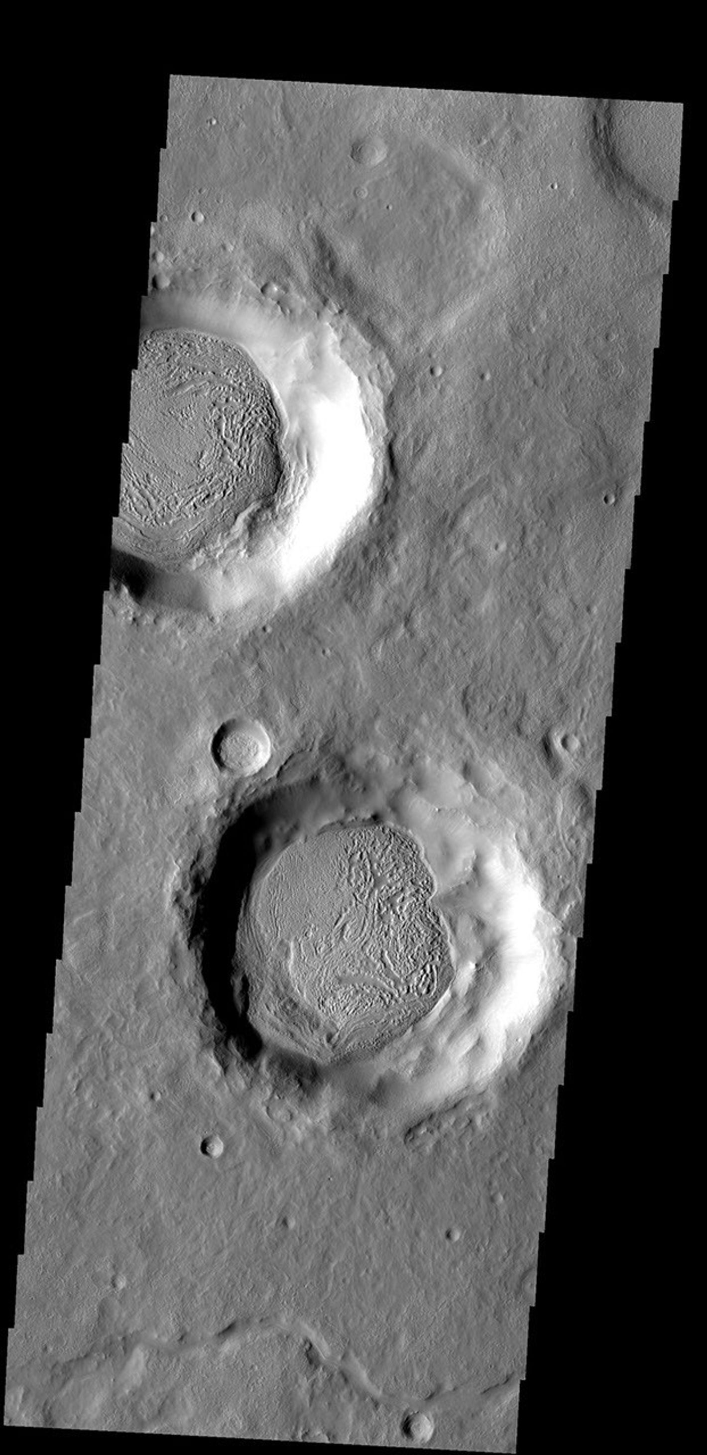 The material covering the floors of these two craters looks very different from the surrounds. The unusual markings of the floor material indicates that ice, has affected the appearance of the surface as seen by NASA's Mars Odyssey spacecraft.