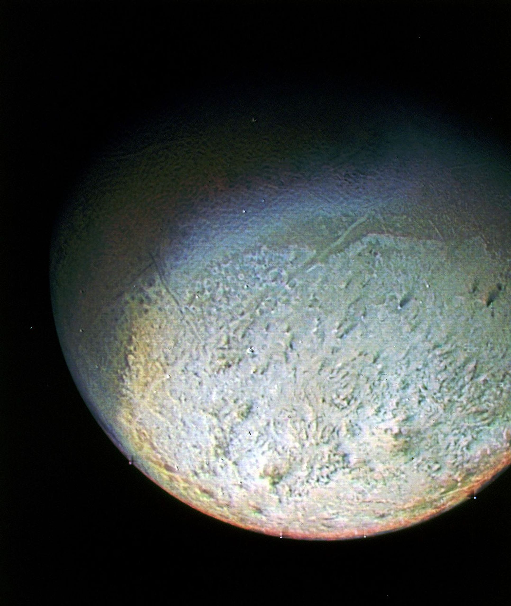 This color photo of Neptune's large satellite Triton was obtained on Aug. 24 1989. In reality, there is no part of Triton that would appear blue to the eye. The bright southern hemisphere of Triton, which fills most of this frame, is generally pink.