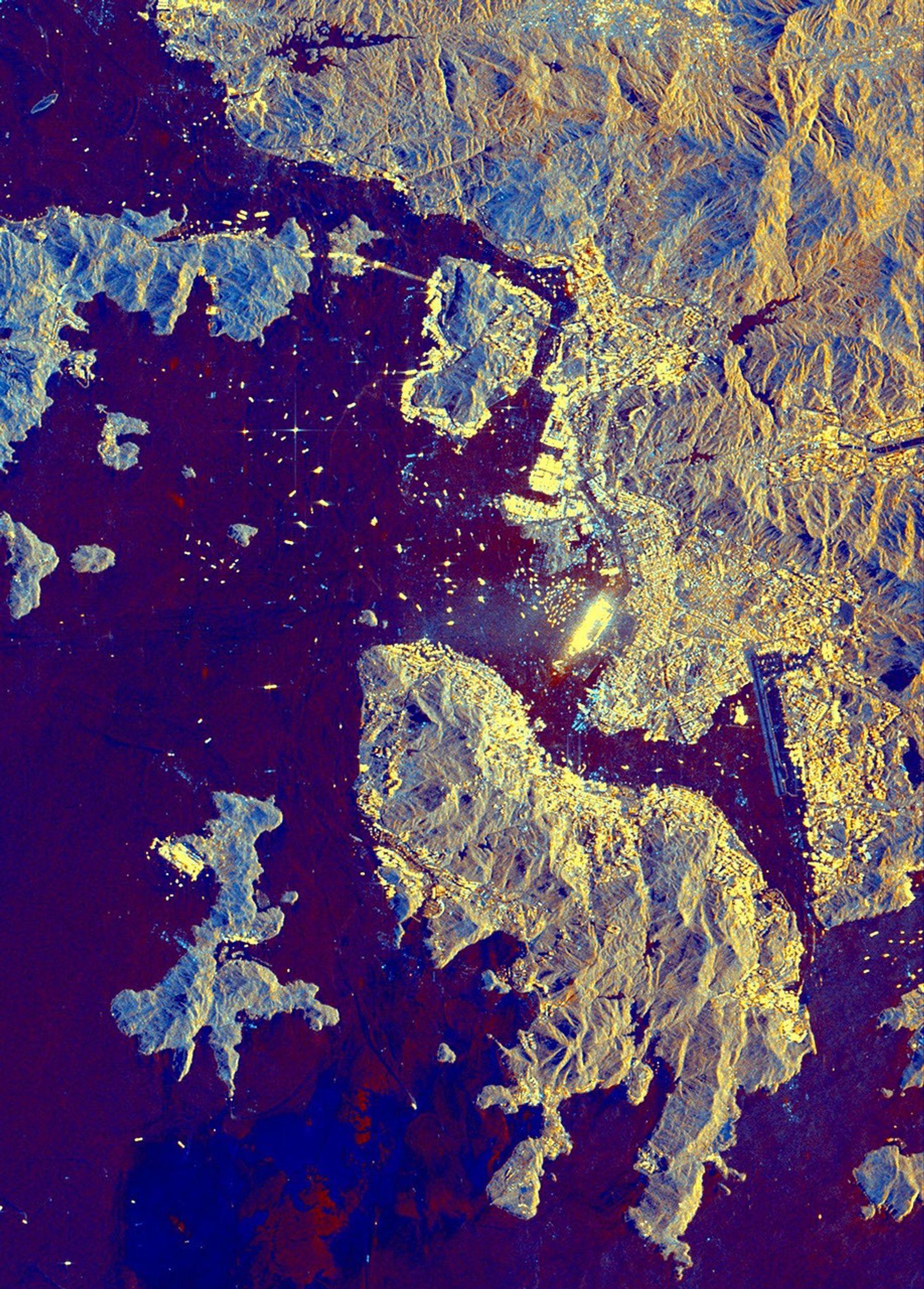 This spaceborne radar image from NASA's Spaceborne Imaging Radar C/X-Band Synthetic Aperture Radar shows part of the British territory of Hong Kong, adjacent to mainland China. The South China Sea is shown in dark blue and red on the image.