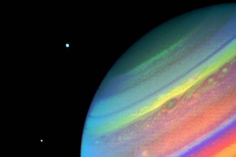 In this image from NASA's Voyager 2 of Saturn, obtained Aug. 11, 1981, from a range of 14.7 million kilometers (9.1 million miles), north is at the upper right edge of the disc. Seen above the planet are the satellites Dione (right) and Enceladus.
