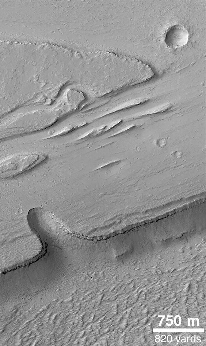 NASA's Mars Global Surveyor shows the Olympica Fossae, a complex array of deep troughs, channels and streamlined landforms in northern Tharsis. Water, mud, and lava are all thought to have played a role in the formation of these features.