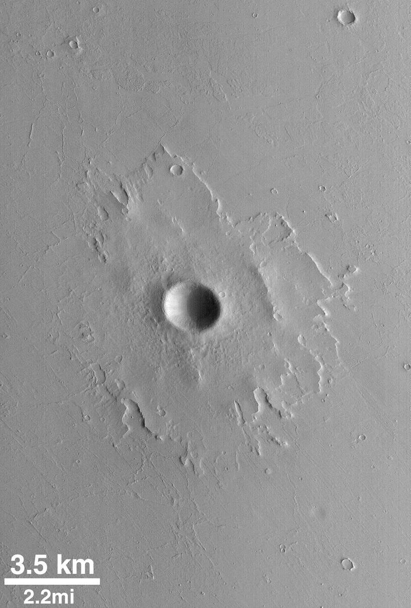 NASA's Mars Global Surveyor shows the upper layer of Martian plains surrounding this impact crater that have been stripped and deflated by wind. The rocky ejecta of the crater, however, protected the material beneath the ejecta blanket from such erosion.