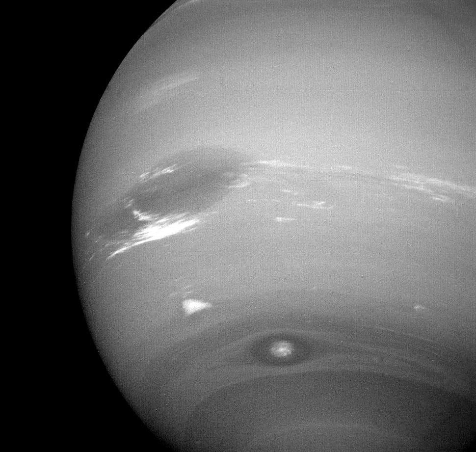 This photograph of Neptune shows three of the features that NASA's Voyager 2 has been photographing during recent weeks. At the north is the Great Dark Spot, accompanied by bright, white clouds that undergo rapid changes in appearance.