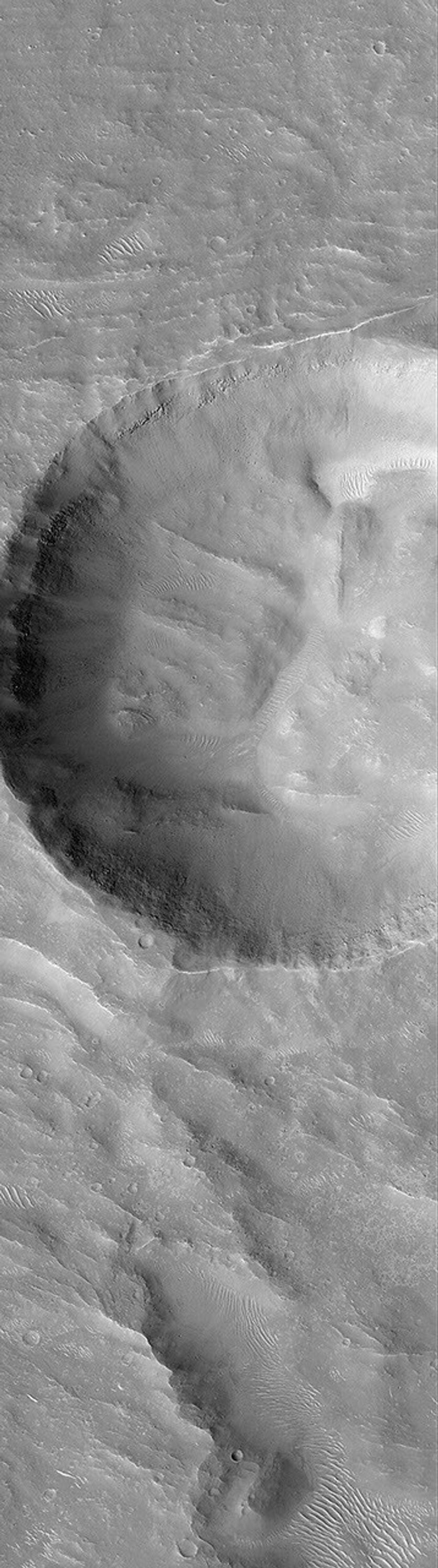 NASA's Mars Global Surveyor shows wide impact crater on the floor of a larger crater in the Nepenthes Mensae region on Mars.
