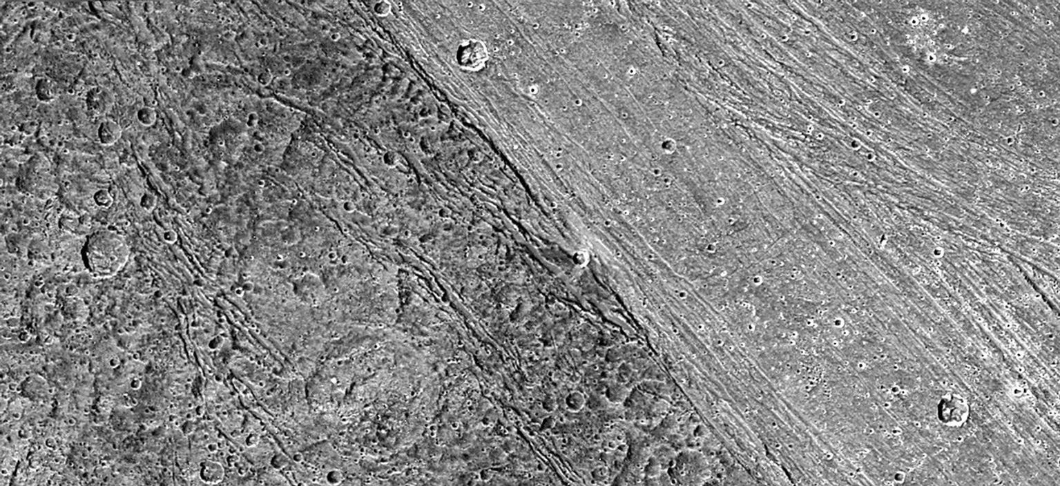 The ancient, dark terrain of Nicholson Regio shows many large impact craters, and zones of fractures oriented generally parallel to the boundary between the dark and bright regions of Jupiter's moon Ganymede. Image taken by NASA's Galileo spacecraft.