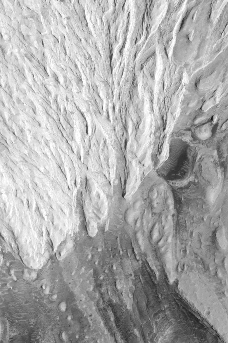 NASA's Mars Global Surveyor shows a circular feature, a partly-exhumed vrater, interpreted to be an ancient impact crater on Mars that formed on the same layered rock surface into a channel.